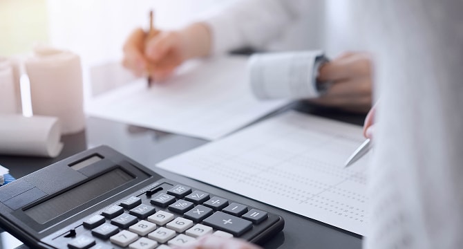 電卓を使って紙に記入している様子